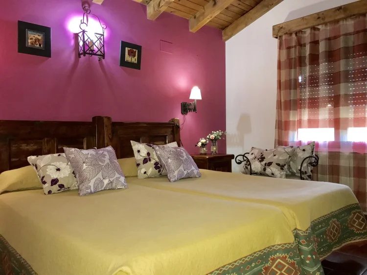 Dormitorio con techo de vigas de madera y cama de matrimonio